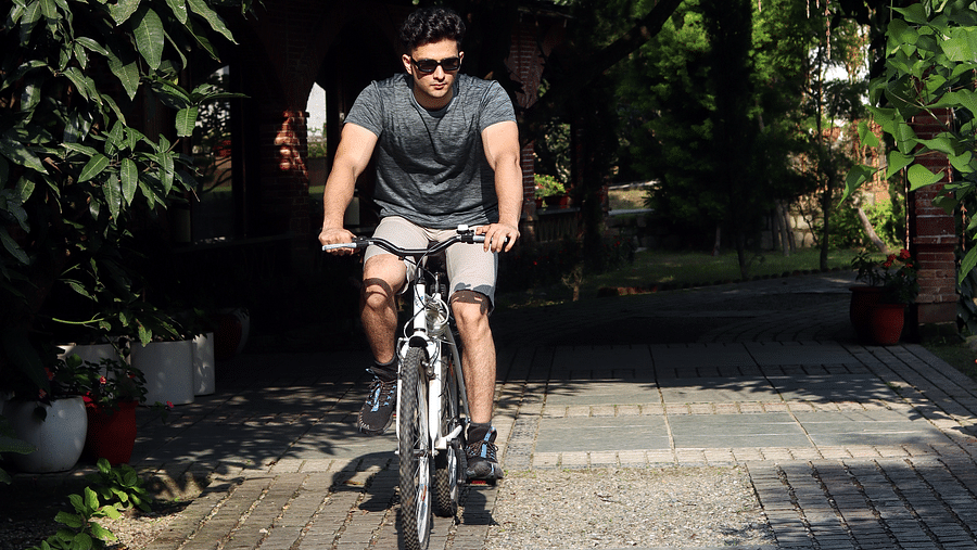 A man cycling on a pathway at A man flying a kite at The Sylvan Retreat, Dehradun.