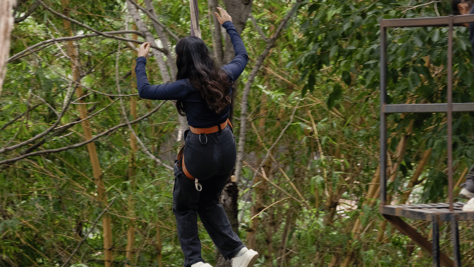 A person in dark clothing is seen zip-lining at RD's Nature Retreat, Bangalore, the perfect place for a Day Outing in Bangalore.