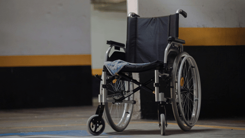 A wheelchair placed in a parking area near concrete pillars at the best resort in Bangalore.
