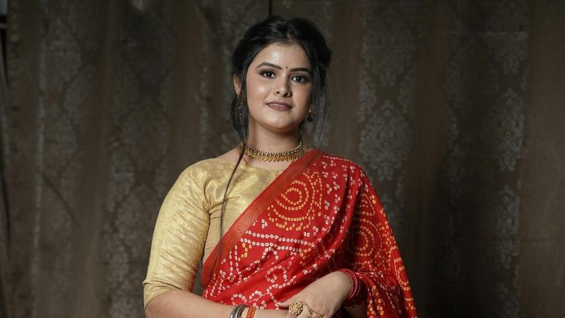A portrait of a woman wearing a red bandhani saree