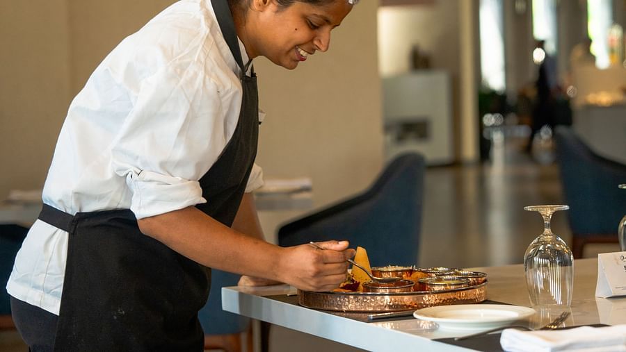 A lady serving the dish at a restaurant at Ananta Spa and Resort, Ajabgarh