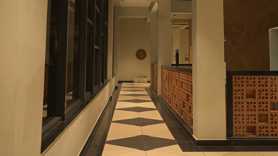 Long white hallway with pattern tiles and white pillars at Hotel Sonar Bangla, Mayapur.