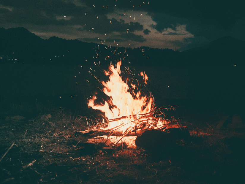 A campfire burning near a waterbody at night.