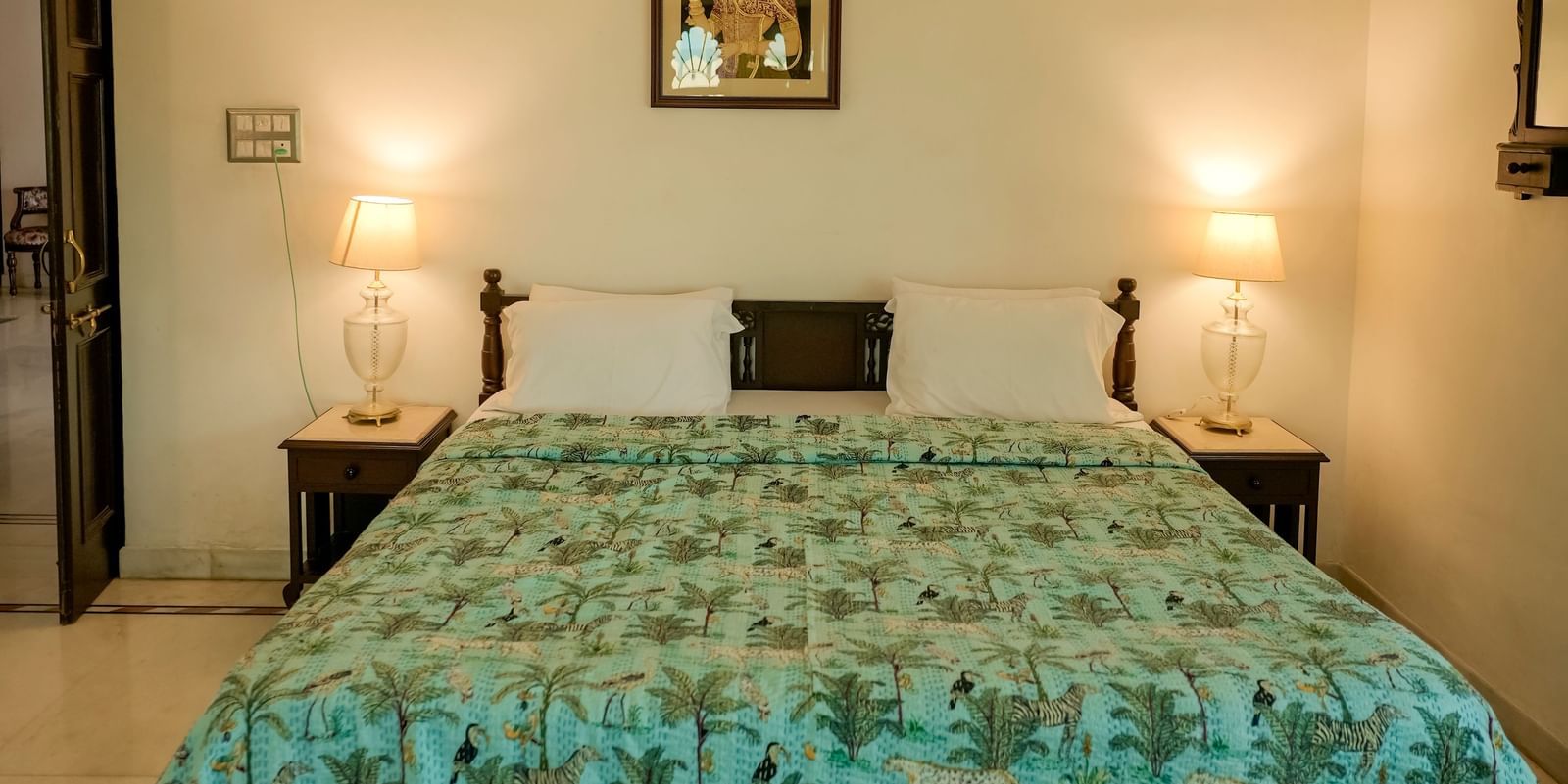 A straight-on view of a bed with a light blue and green patterned duvet in the Heritage Courtyard Room at Mahendra Niwas.