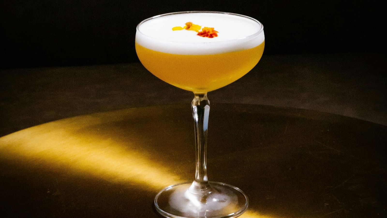 A cocktail served in a glass placed on a wooden surface.