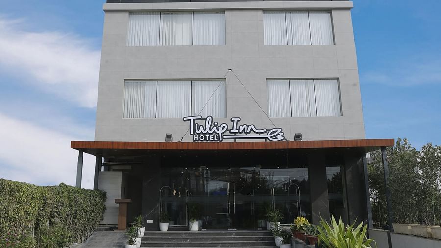 An image of our hotel building with the name of the hotel attached on the signboard and a blue sky in the background - Tulip Inn, Zirakpur