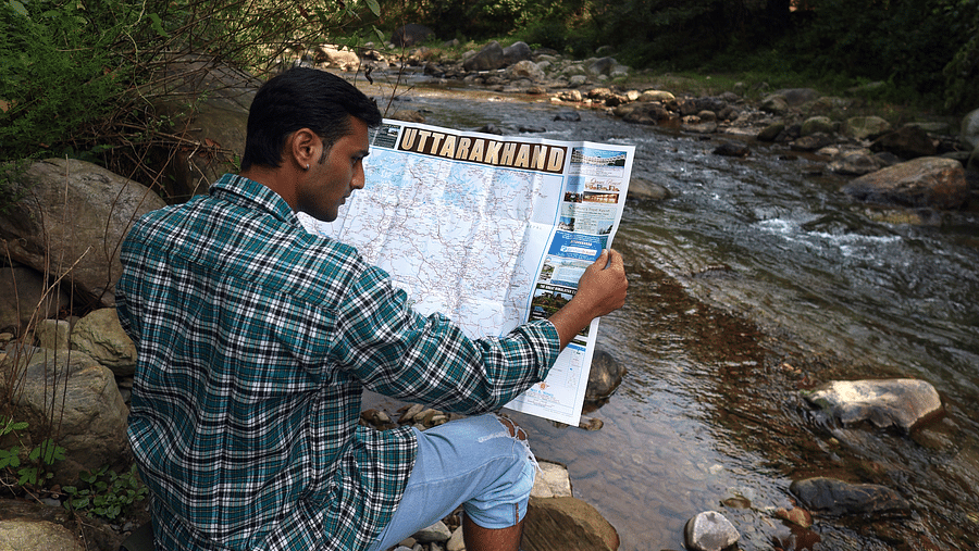 A man reading a map sitting near the stream at A man flying a kite at The Sylvan Retreat, Dehradun.