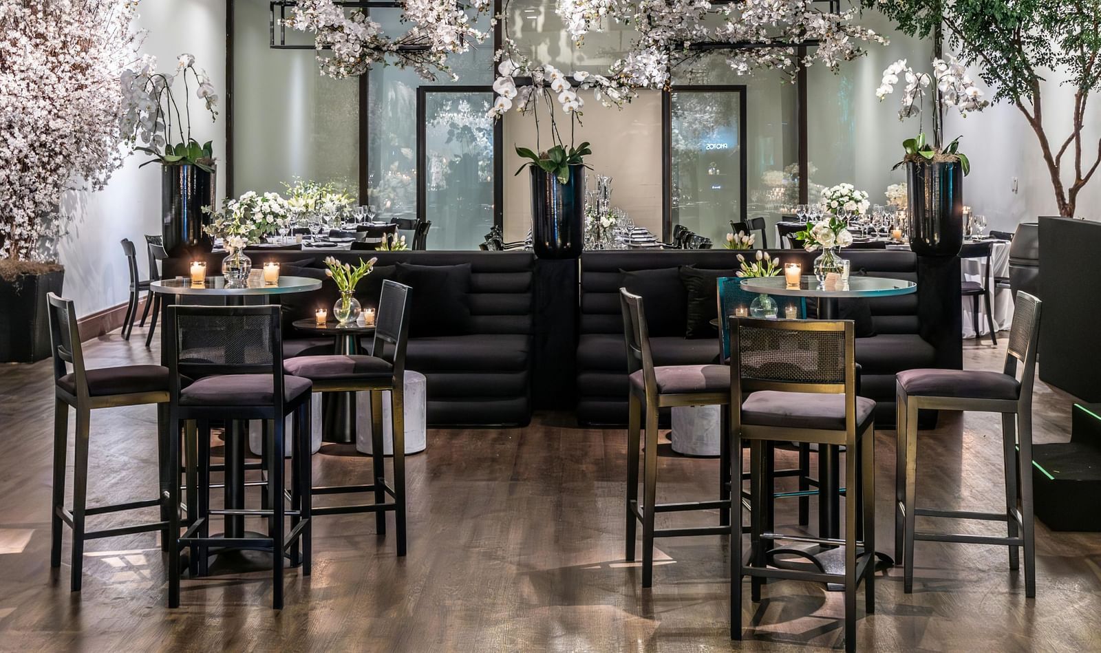 Brightly lit indoor event space with small tables, chairs, and floral decorations.
