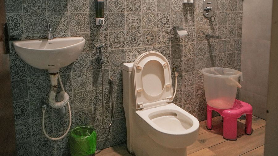 A room at WOW Naturefull Resorts, Yercaud, with a toilet seat, a sink, a mirror, and a shower head.