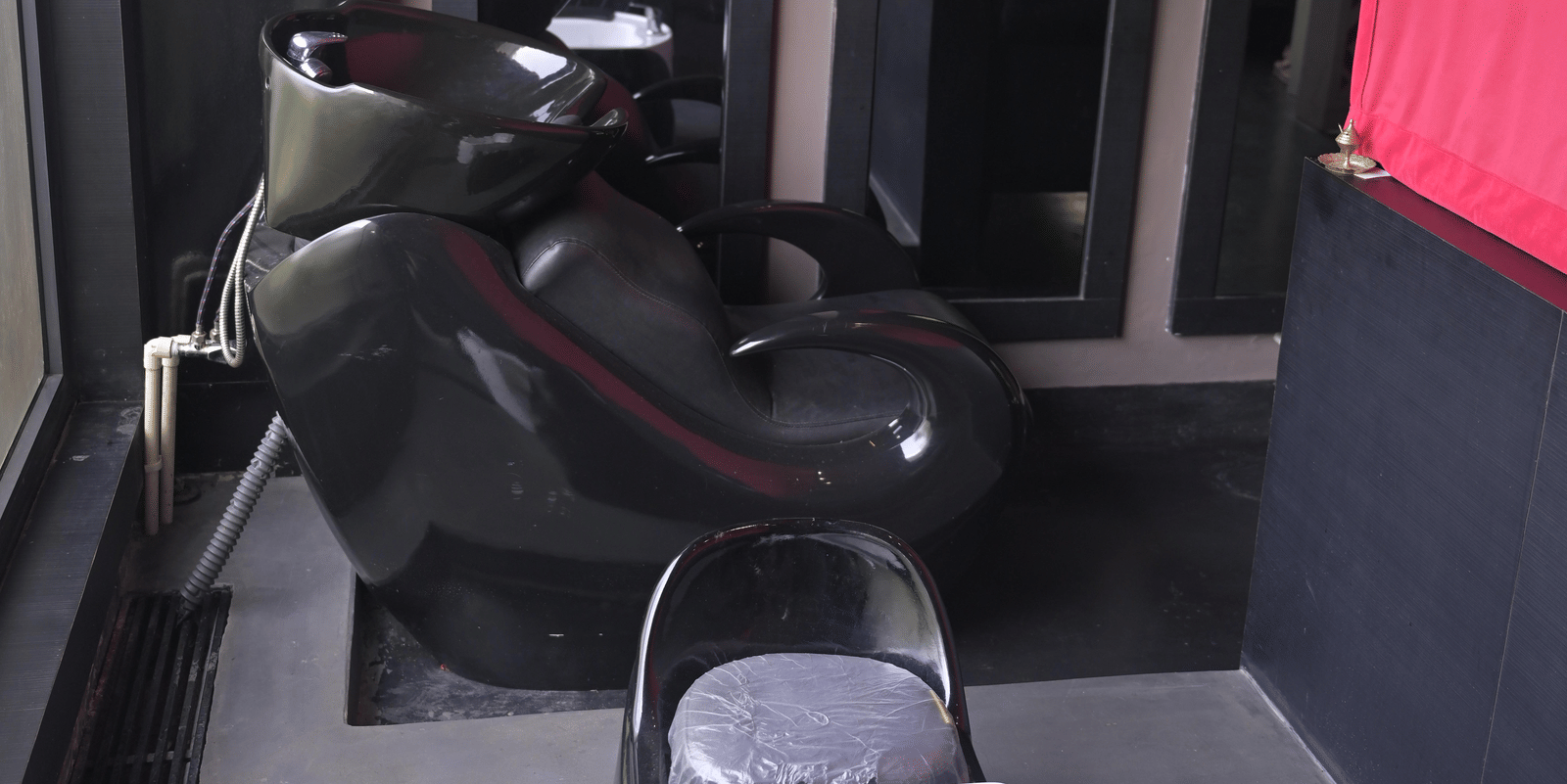 A salon station with a styling chair and wash basin in a modern setup at Hotel Sonar Bangla Mayapur.