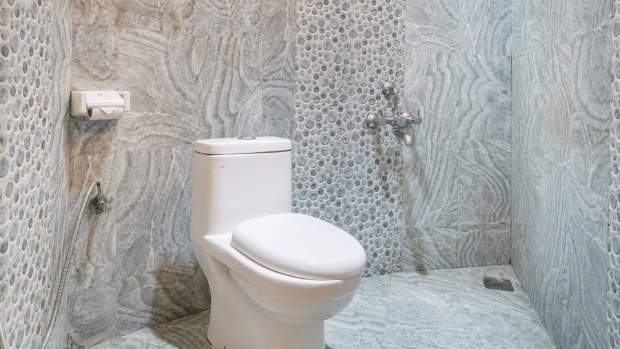 Image of a washroom with a toilet and a geyser mounted on the wall at Coorg Jungle Camp Backwater Resort, Kushalnagar.