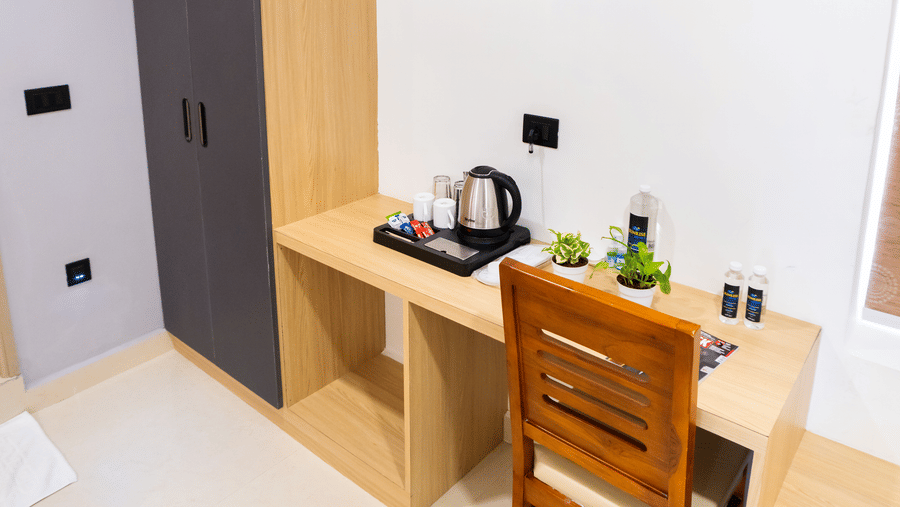 A room corner with a desk, chair, and cabinets, with a wall-mounted A/C above them at Sunrise Business Hotel, Hyderabad.