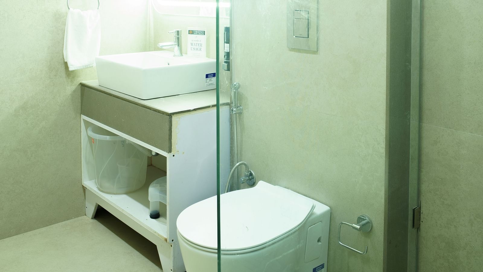 A bathroom at Orsino Spa Resort with a toilet and basin, enclosed within a glass shower cubicle.
