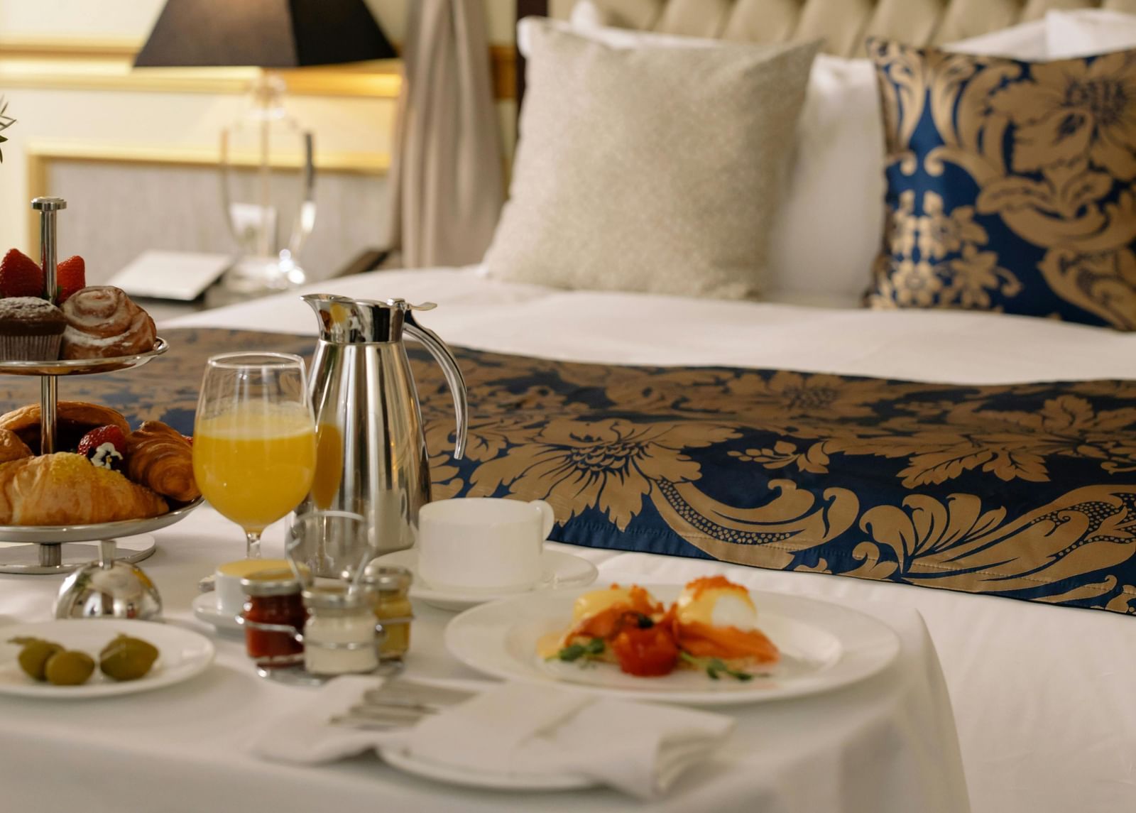 Elegant hotel room with a luxurious bed and breakfast served on a table.
