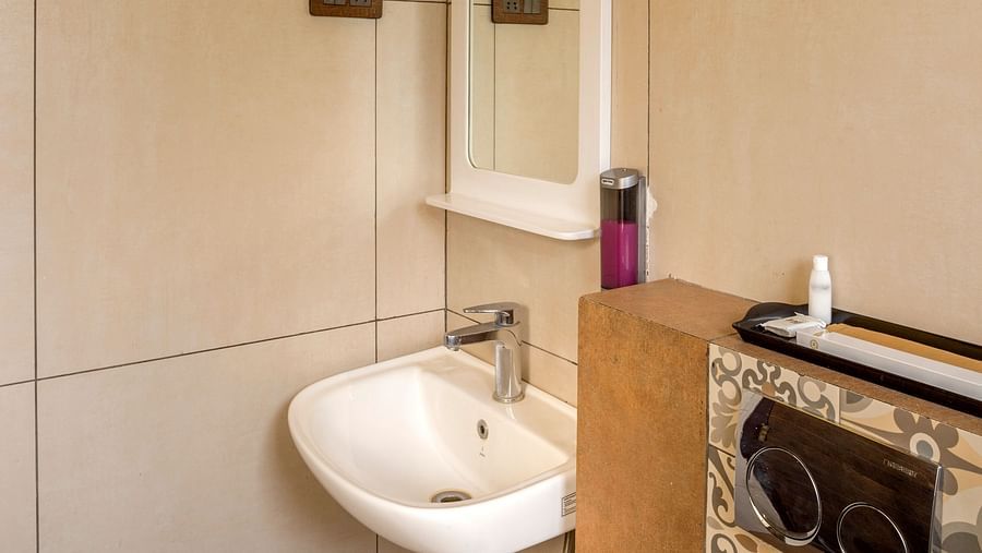 Compact bathroom with yellow accent wall and modern fixtures at Nirantara Resort & Spa