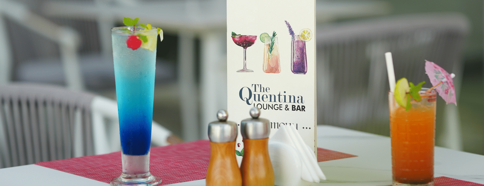 Outdoor cafe table setup from The Quentina Bar featuring cocktails and a menu card - Grande Bay Resort & Spa, Mamallapuram
