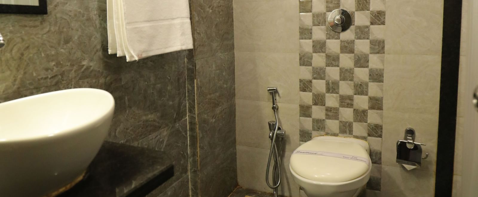 A well-maintained bathroom at Krushnai Resort with a sink, mirror, and a western commode.