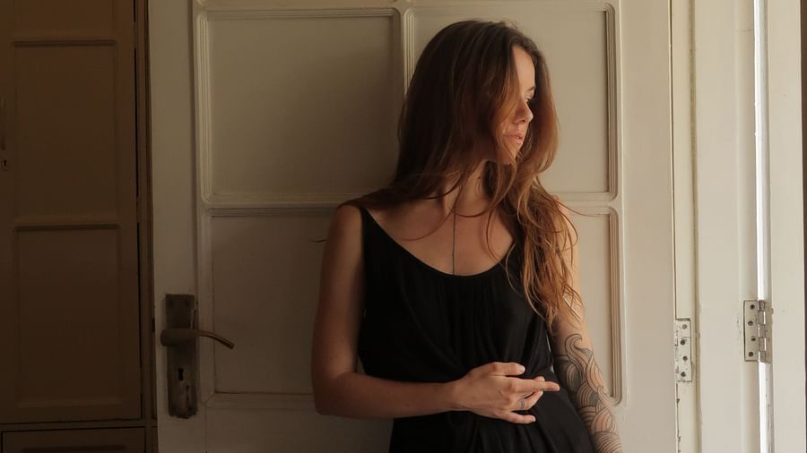  A woman in a black dress standing by an open door, looking away from the camera.