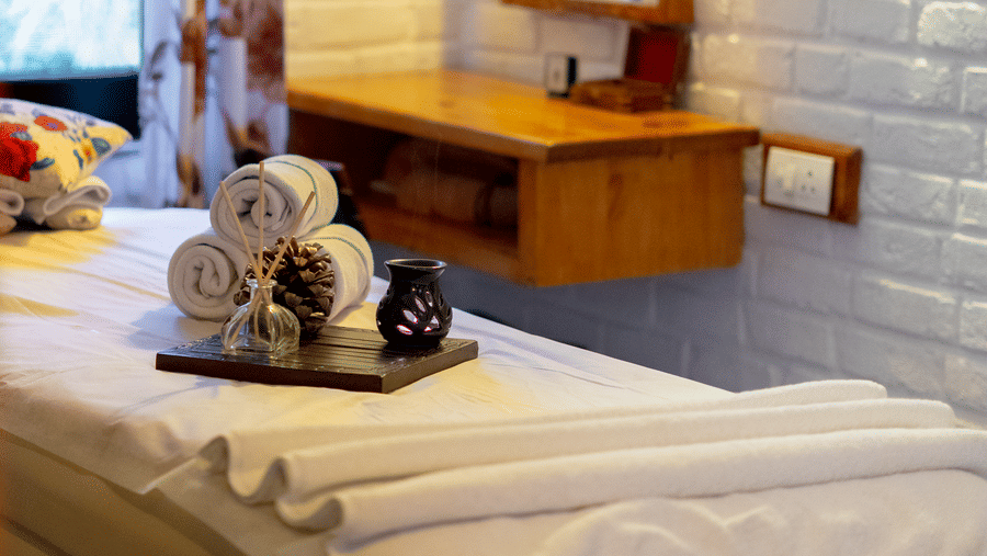 A close-up of a spa vanity area with a wooden mirror frame against a white-painted brick wall - Johnson Lodge & Spa, Manali