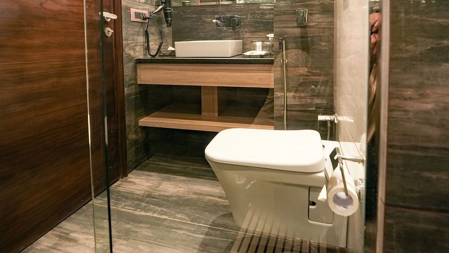 An image of a washroom with a commode and a sink placed under a wall-mounted mirror - NAMAMI BY ZENQ BANKHANDI