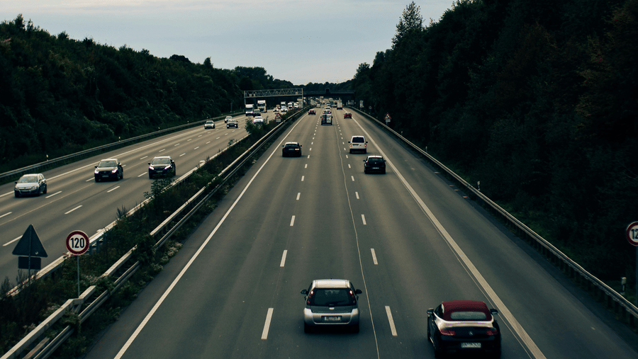 An overview of a 6-lane highway with cars travelling on both directions and trees on either side of the road, as seen during the Pune to Goa trip by road.