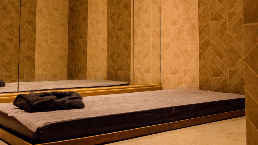 A mattress kept on the floor of a dimly lit room with a wall attached with full length mirror at Benzz Park, Vellore.