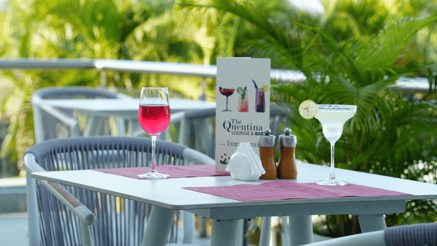 Outdoor table with chairs arranged beside plants and a menu card on the table at Grande Bay Resort & Spa.