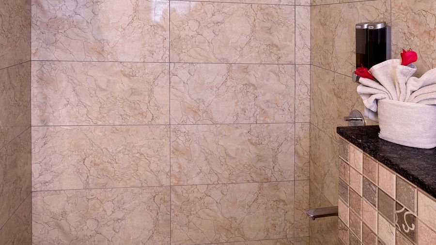 Clean bathroom with walk-in shower and tiled walls – Nirantara Resort & Spa