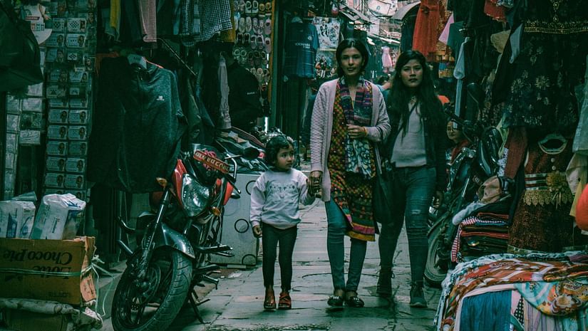 An image of a market with shops on either side and a woman walking with her child