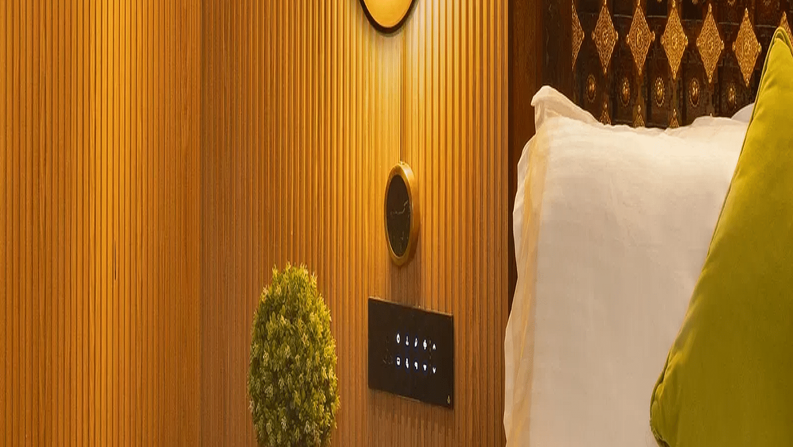 Coral Teal Suite at Coral Reef Resort and Spa in Havelock featuring a plush bed placed against the patterned wall with warm lighting and a nightstand next to it over which is a lamp
