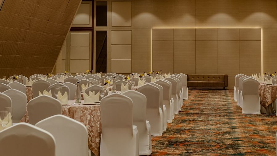 A view of the speaker table from the audience end in a party hall in ajmer featuring warm lighting and carpeted floors - Sarovar Portico, Ajmer