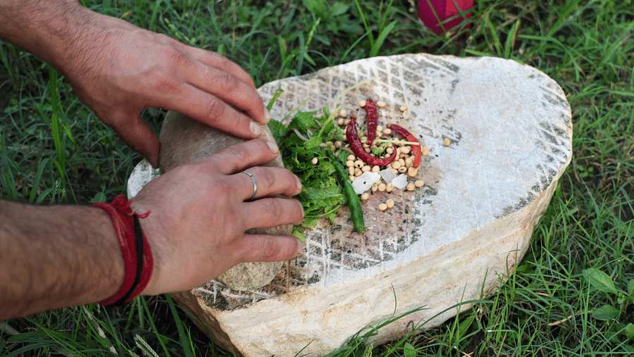 A close up shot of chef preparing a spice mix in a grassfield at the Sylvan Retreat, Dehradun.