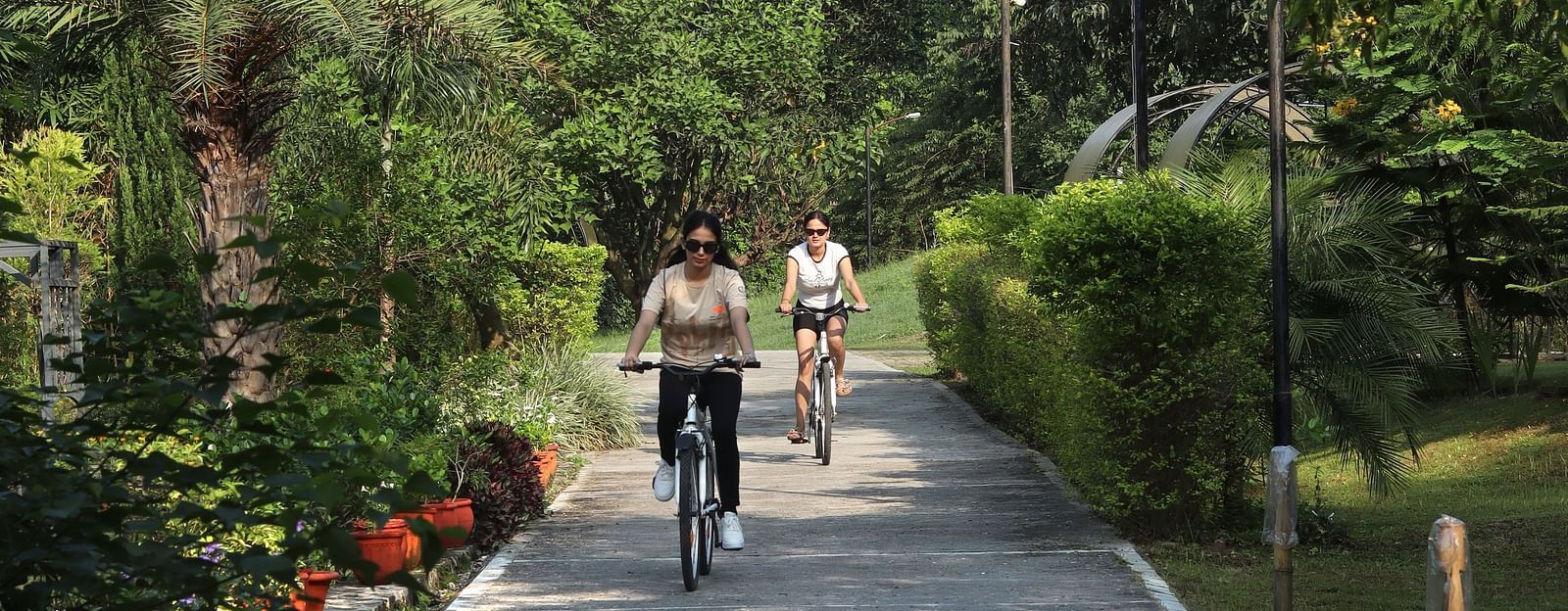 A view of a pathway with people cycling on it at A man flying a kite at The Sylvan Retreat, Dehradun.