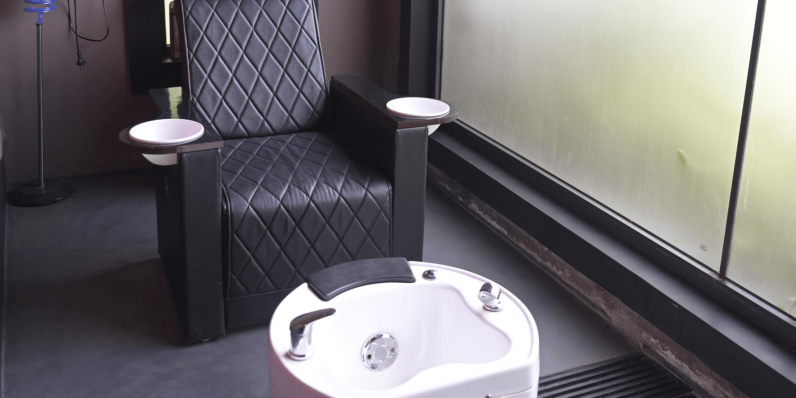 A pedicure station with a foot spa tub beside a large window at Hotel Sonar Bangla Mayapur.