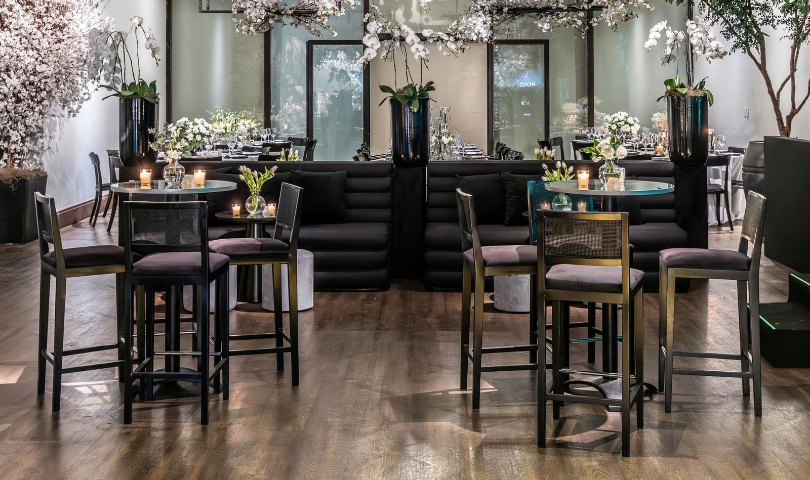 Brightly lit indoor event space with small tables, chairs, and floral decorations.