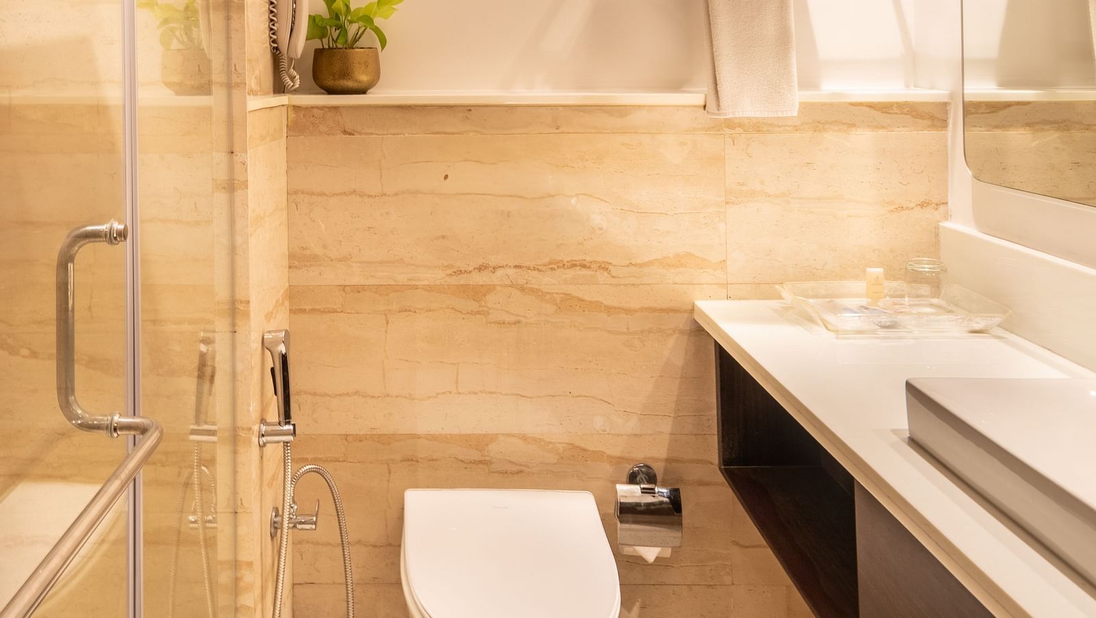 A narrow view of a bathroom with a toilet and a shower area of Superior Room- TGI Grand Fortuna, Krishnagiri Main Road, Hosur
