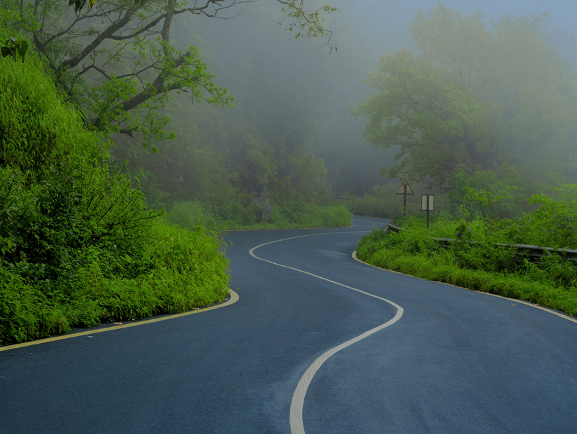 A fog covered hubali-goa highway with thick green trees and canopies on both sides.