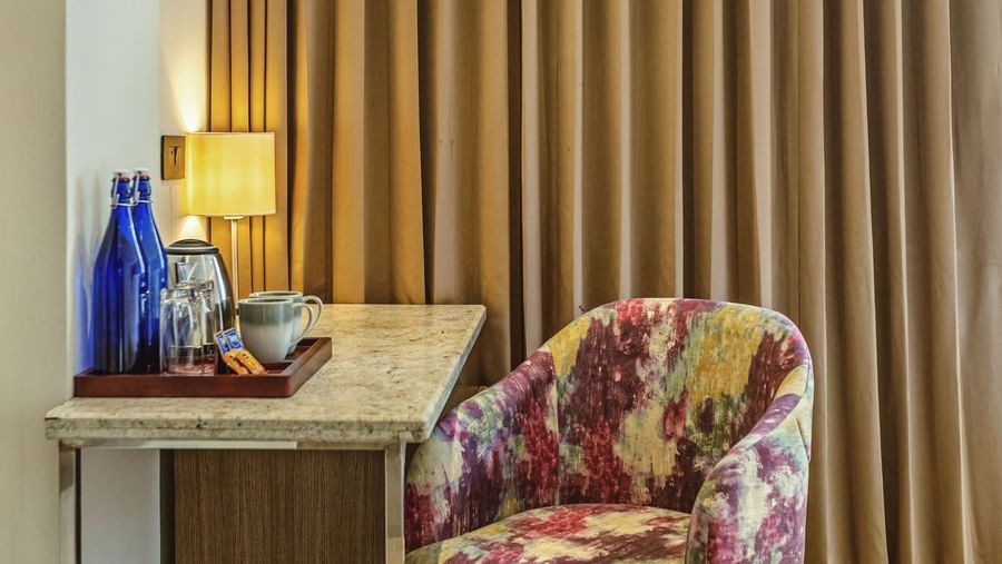 A close-up of a desk with a chair in a room at Mango Hill Central, Chennai. Gold curtains hang behind the desk.