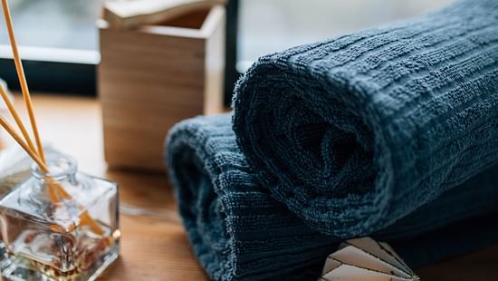 Two rolled towels beside incense sticks and a wooden box near the window.