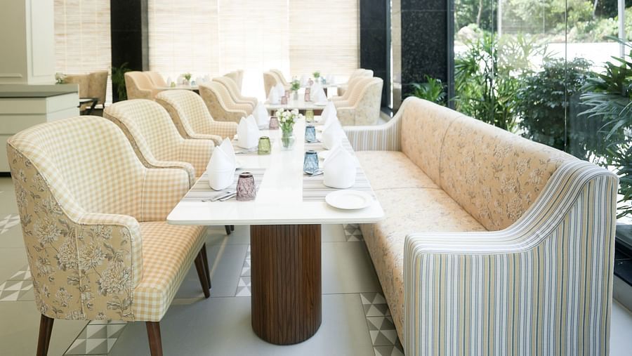 An image of NUTMEGG restaurant in Kangra, highlighting a table positioned beside a tall window that extends from the floor to the ceiling - NAMAMI BY ZENQ BANKHANDI