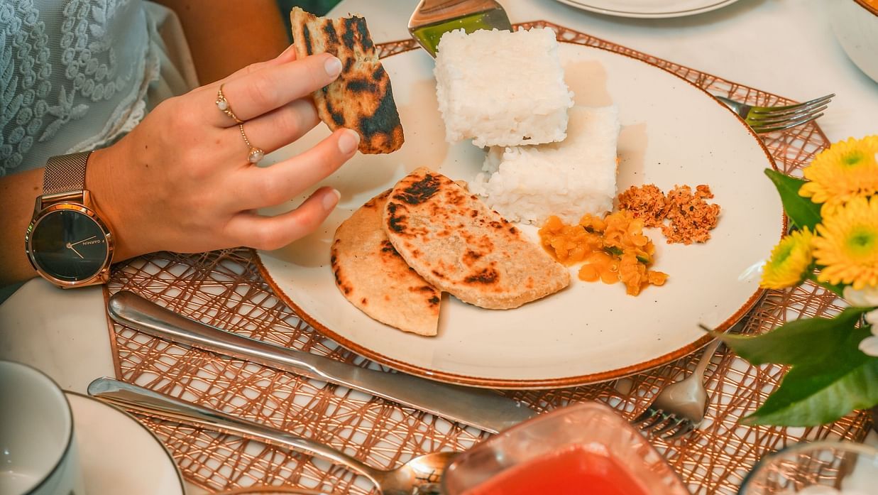 Close-up of a table with hands serving traditional dishes in a warm and inviting setting - Heavensa Villas and Suites by the Clarks, Galle