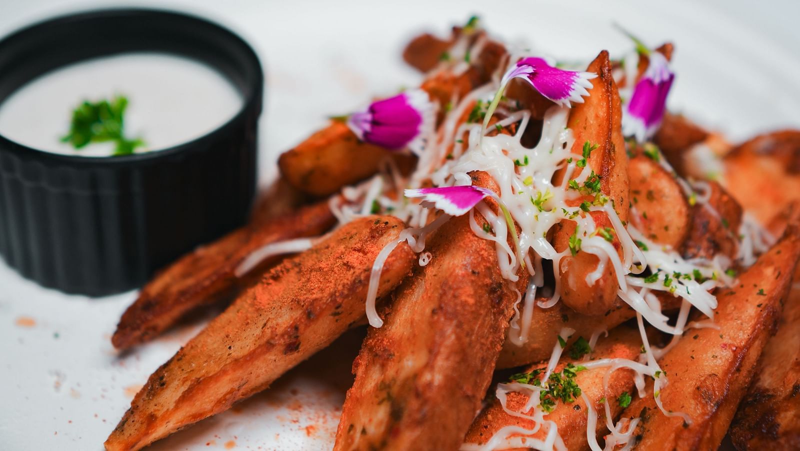 Crispy seasoned wedges topped with shredded cheese and microgreens, served with a creamy dip at D Café, Dip Holidays.