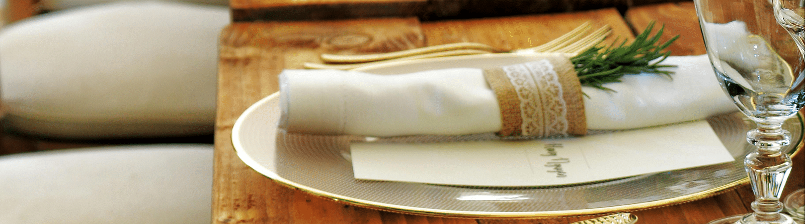 A long, elegantly set dining table stretches into the distance, featuring tables aranged with plates and napkins.