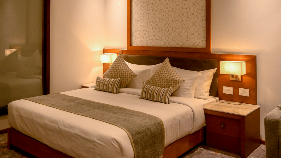  A bedroom featuring a king size bed with bedside tables and lit lamps against a patterned wall panel at Tiara by MPS.