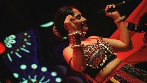 Close-up of a female singer on stage with decorative lighting in the background.