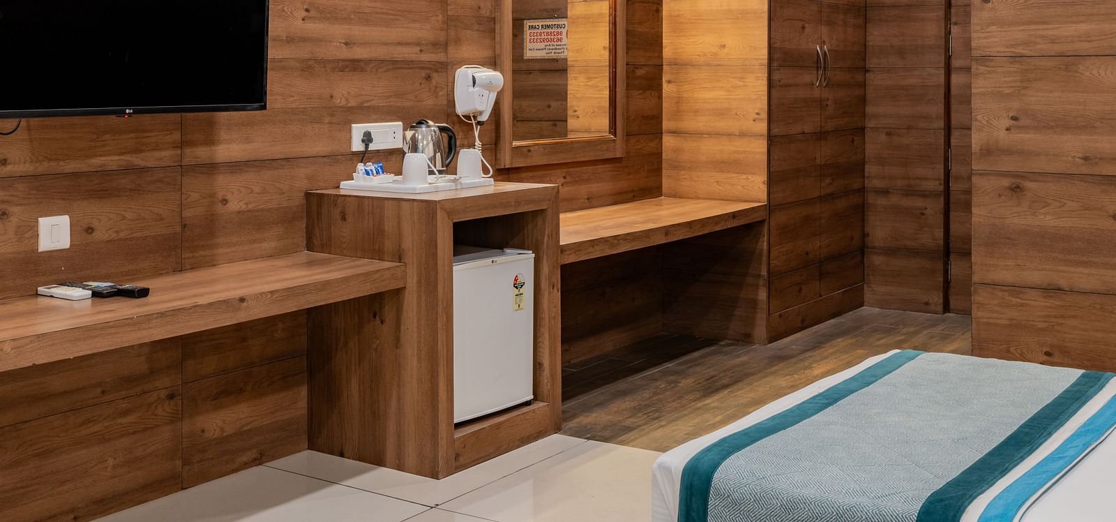 Compact King Twin Bed Room setup with mounted TV, minibar, and wood finishes at Hotel Highway King, Bilaspur.