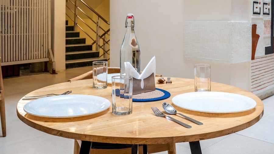 A round dining table set for 2 with plates, glasses, and cutlery - Monday Hotels HITEC City, Hyderabad