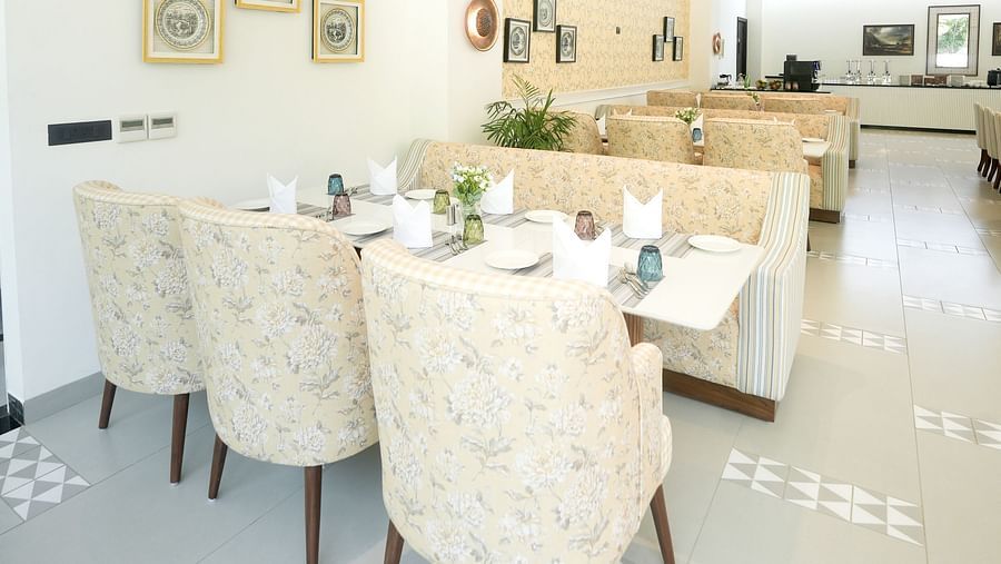 A portrait image of a restaurant featuring upholstered chairs and sofas arranged around the dining tables - NAMAMI BY ZENQ BANKHANDI
