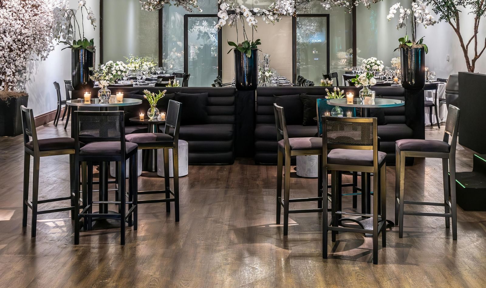 Brightly lit indoor event space with small tables, chairs, and floral decorations.
