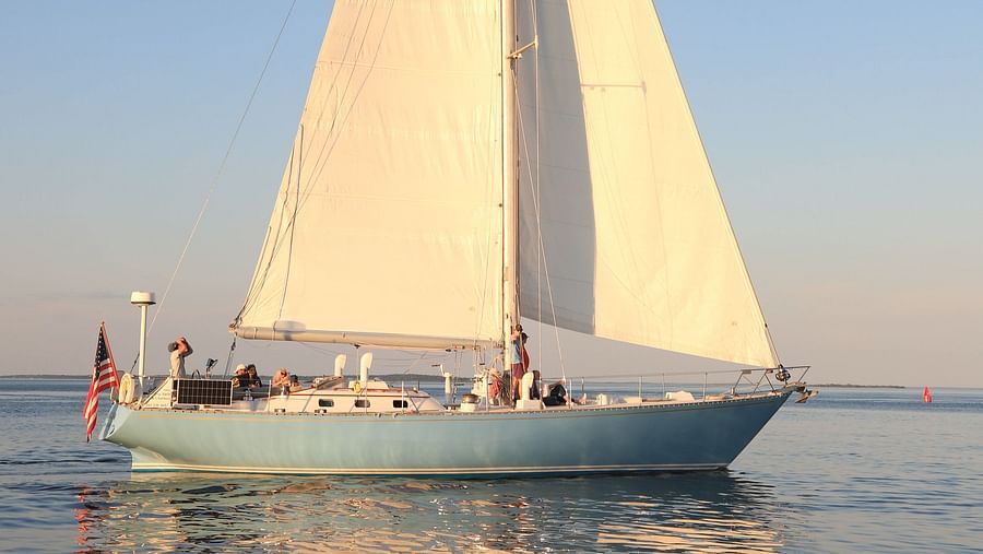 White sailboat gliding on calm waters at sunset near Hartstone Inn.